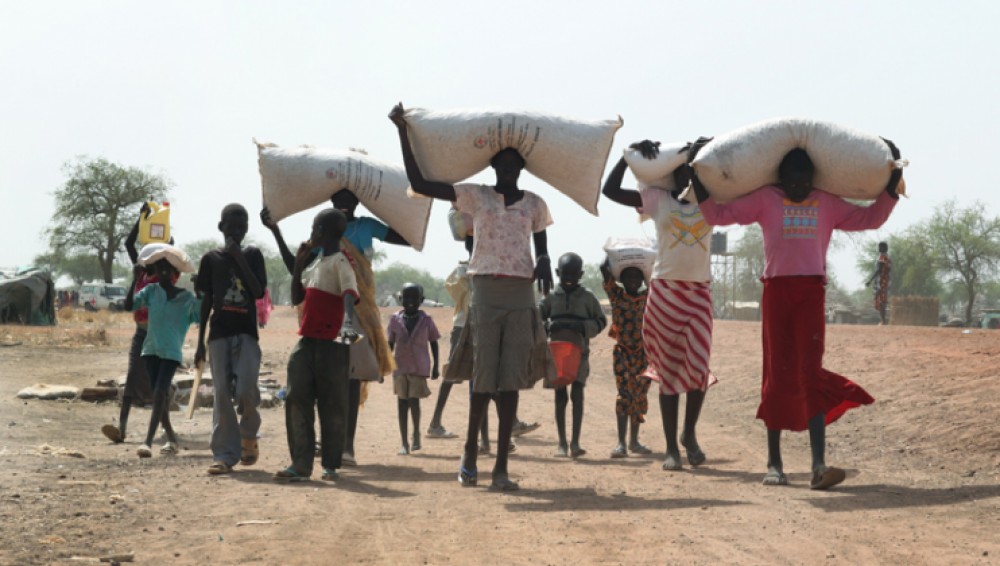 Villagers take from ICRC distribution point oil and seeds 