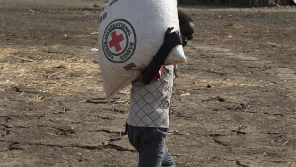 Boy walks on parched land carrying a bag of seed. First rains are due in late April, marking the start of planting season. 