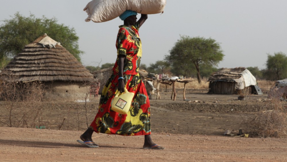 Woman carries oil and seed.  She, like many, lost her crops fleeing fighting in May 2011. 