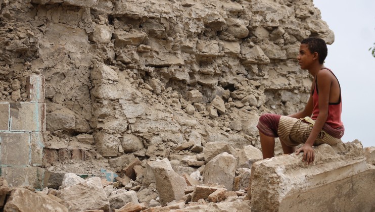 A young boy sits in the ruins of his family?s home in Yemen.