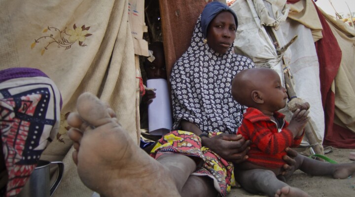 Amina, 25 ans, est assise à l’ombre avec son fils de 2 ans, Aliyu. Leur abri de fortune n’est pas solide mais il les protège du soleil brûlant de Maiduguri. On aperçoit Hassan, le fils aîné d’Amina, caché dans l’abri.