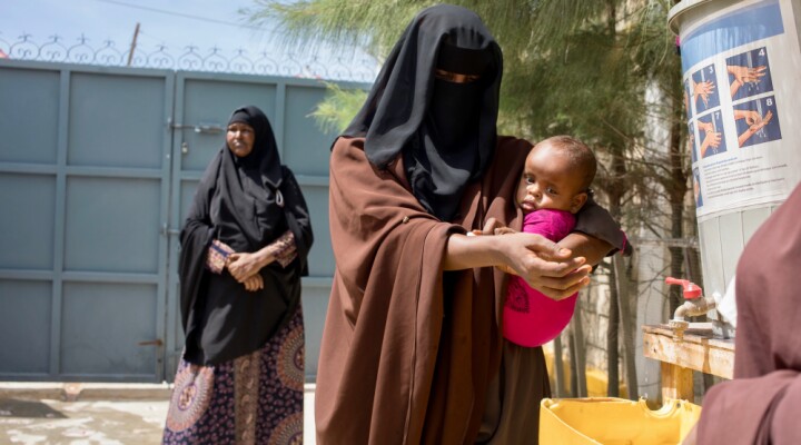 Handwashing stations have been setup across all Somali Red Crescent Socity (SRCS) clinics in South and Central Somalia. A mother washese her hands at the entrance of the SRCS clinic. ICRC/Ismail Taxta