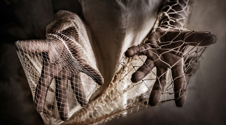 Malian fisherman Ba Seydou displays two fishing nets: he used the one in his left hand 25 years ago; in his right hand, he holds the net he has to use now, because the fish are getting smaller and smaller.  Samuel Turpin/ ICRC  Part of Humans & Climate Change documentary project.
